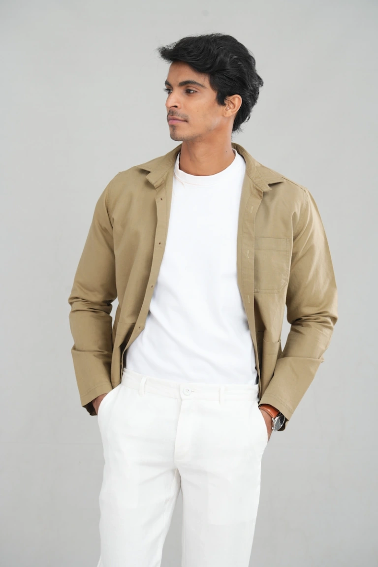 A model wearing a sand-tan overshirt jacket with long sleeves, button-up design, and multiple utility pockets, ideal for casual layering and versatile everyday wear.