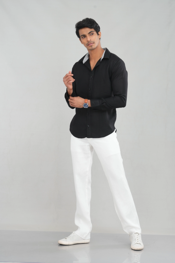 Model wearing a black linen long-sleeve shirt with a button-down design, paired with white trousers for a sharp and versatile look.