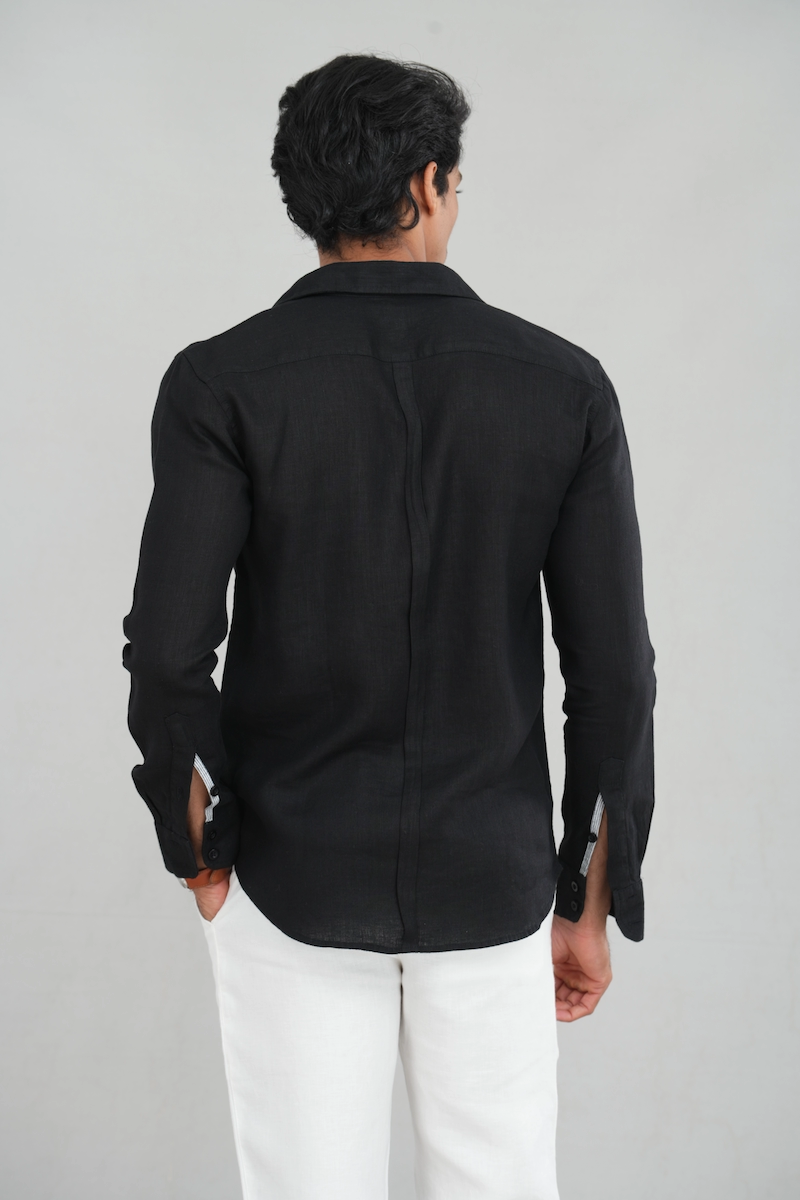 Model wearing a black linen long-sleeve shirt with a button-down design, paired with white trousers for a sharp and versatile look.