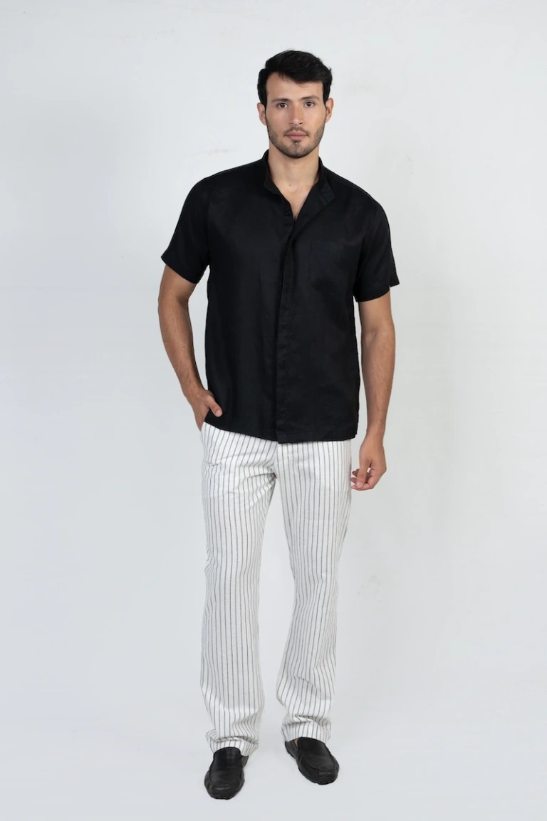 A model wearing a relaxed fit short sleeve black linen shirt with a button-up design and a chest pocket, perfect for casual summer outings or everyday wear.