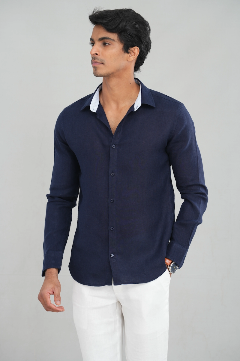 A model wearing a long sleeve linen shirt in a deep navy blue shade, featuring a classic button-up design and lightweight fabric, perfect for casual summer wear or stylish everyday outfits.