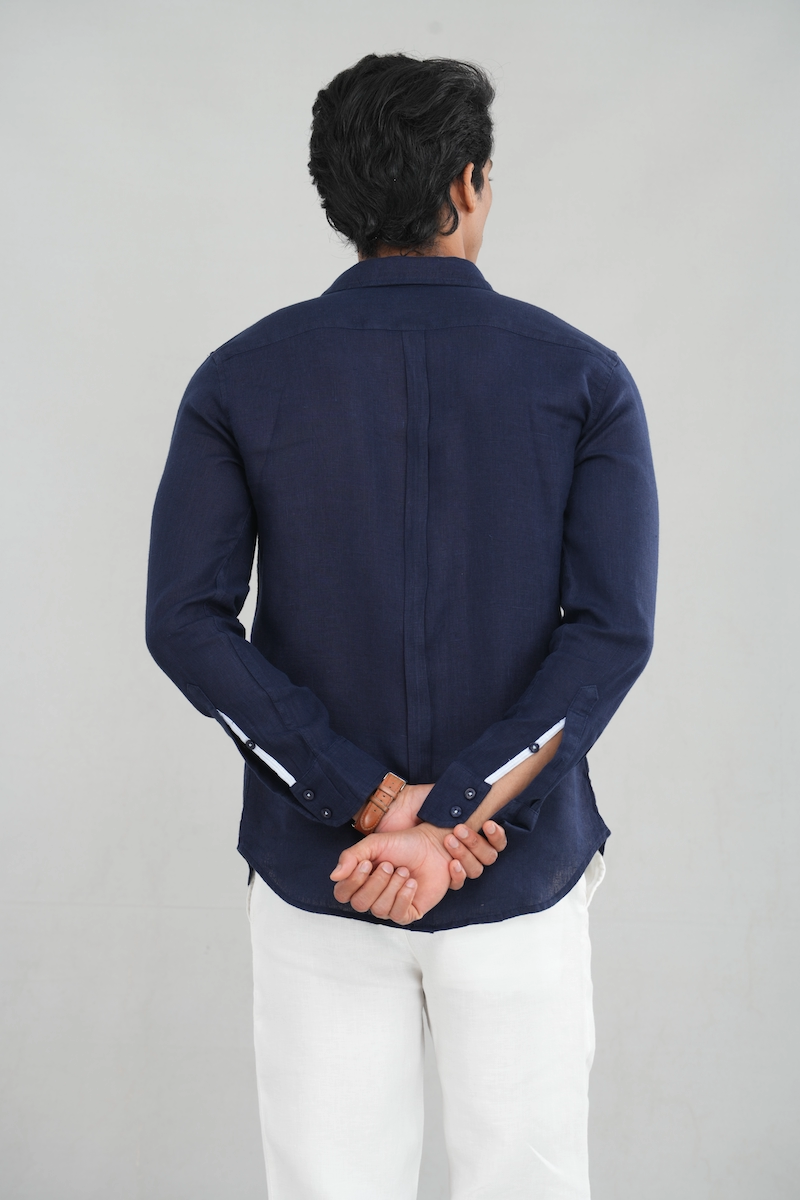 A model wearing a long sleeve linen shirt in a deep navy blue shade, featuring a classic button-up design and lightweight fabric, perfect for casual summer wear or stylish everyday outfits.