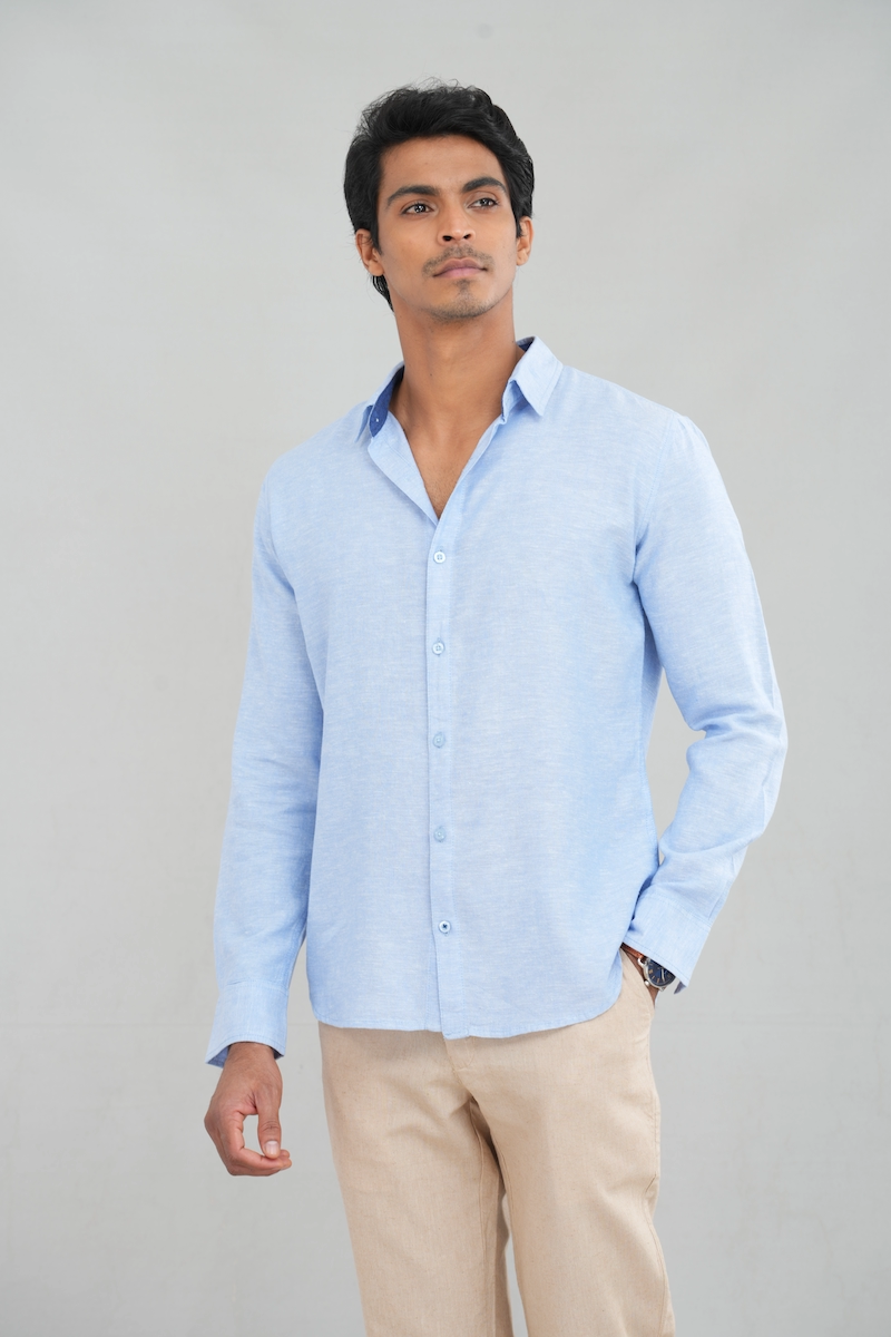 A model wearing a long sleeve linen shirt in a light blue shade, featuring a classic button-up design, perfect for casual summer wear or stylish everyday outfits.