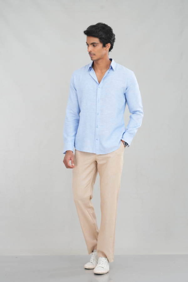 A model wearing a long sleeve linen shirt in a light blue shade, featuring a classic button-up design, perfect for casual summer wear or stylish everyday outfits.