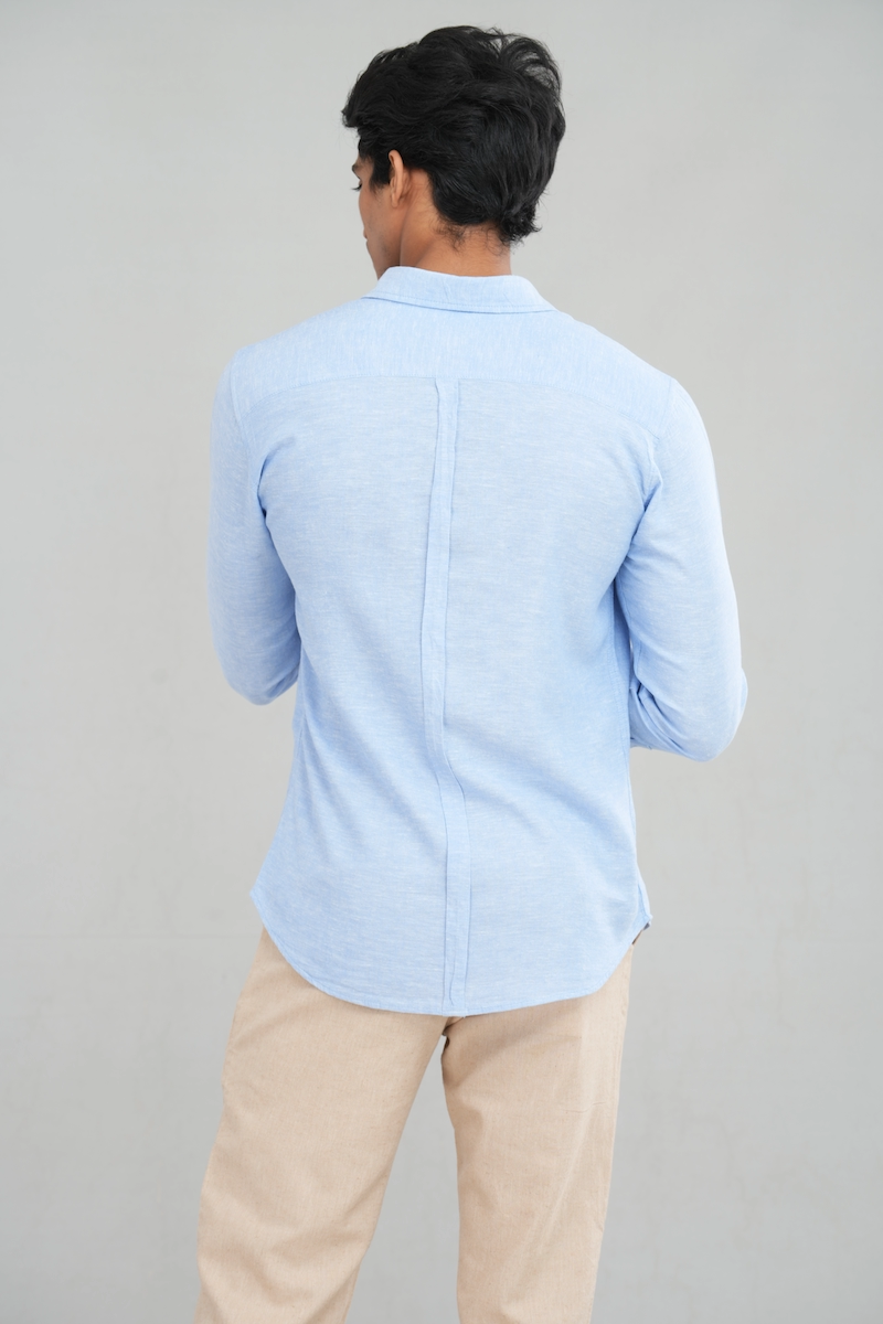 A model wearing a long sleeve linen shirt in a light blue shade, featuring a classic button-up design, perfect for casual summer wear or stylish everyday outfits.