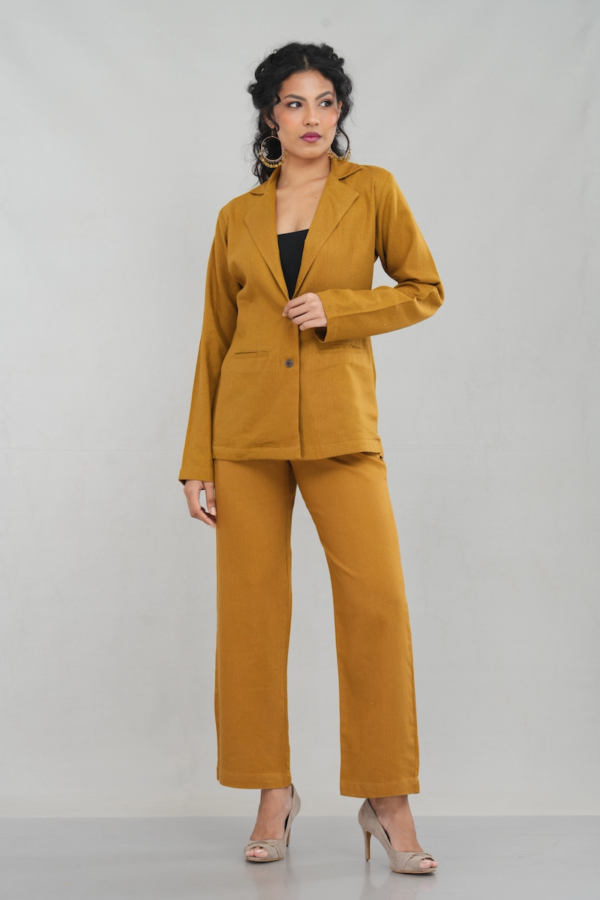 A stylish woman wearing a goldenrod oversized two-button blazer made of linen cotton blend, featuring a sleek lapel design and practical front pockets, paired with matching trousers.