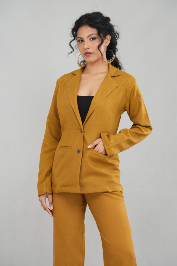 A stylish woman wearing a goldenrod oversized two-button blazer made of linen cotton blend, featuring a sleek lapel design and practical front pockets, paired with matching trousers.