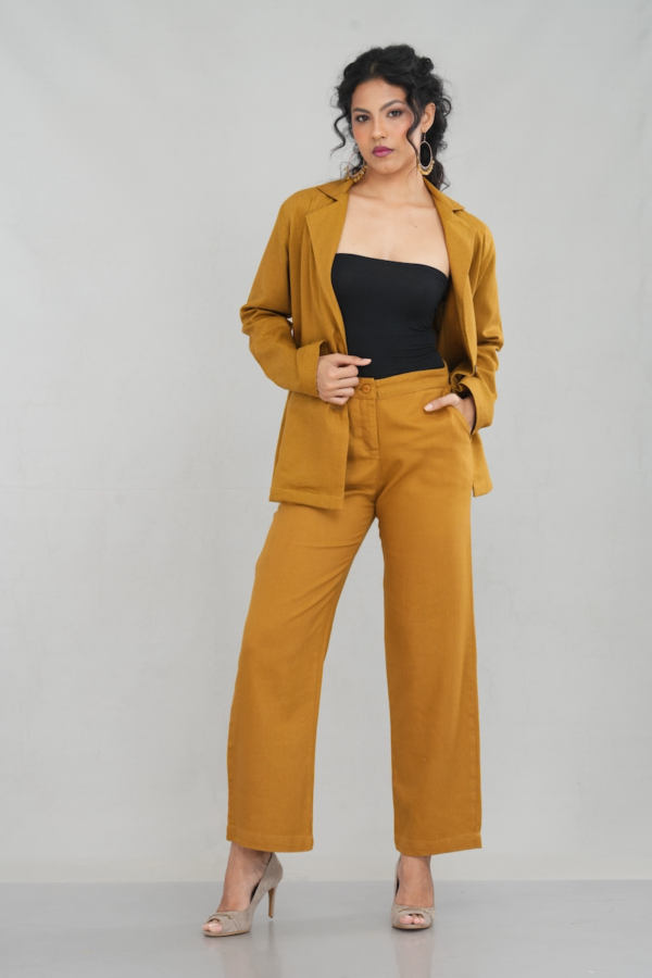 A stylish woman wearing a goldenrod oversized two-button blazer made of linen cotton blend, featuring a sleek lapel design and practical front pockets, paired with matching trousers.