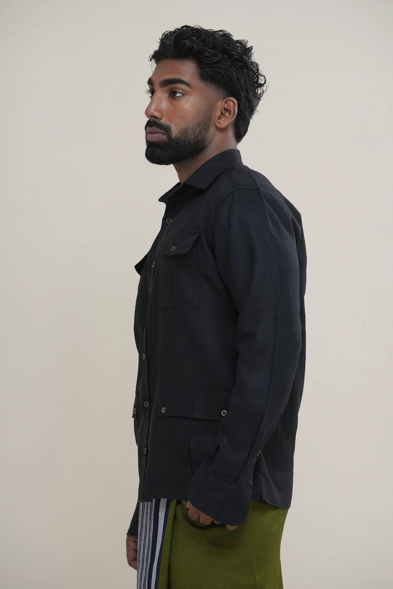 Man wearing a matte black long sleeve utility shirt with four front flap pockets, paired with a patterned sarong