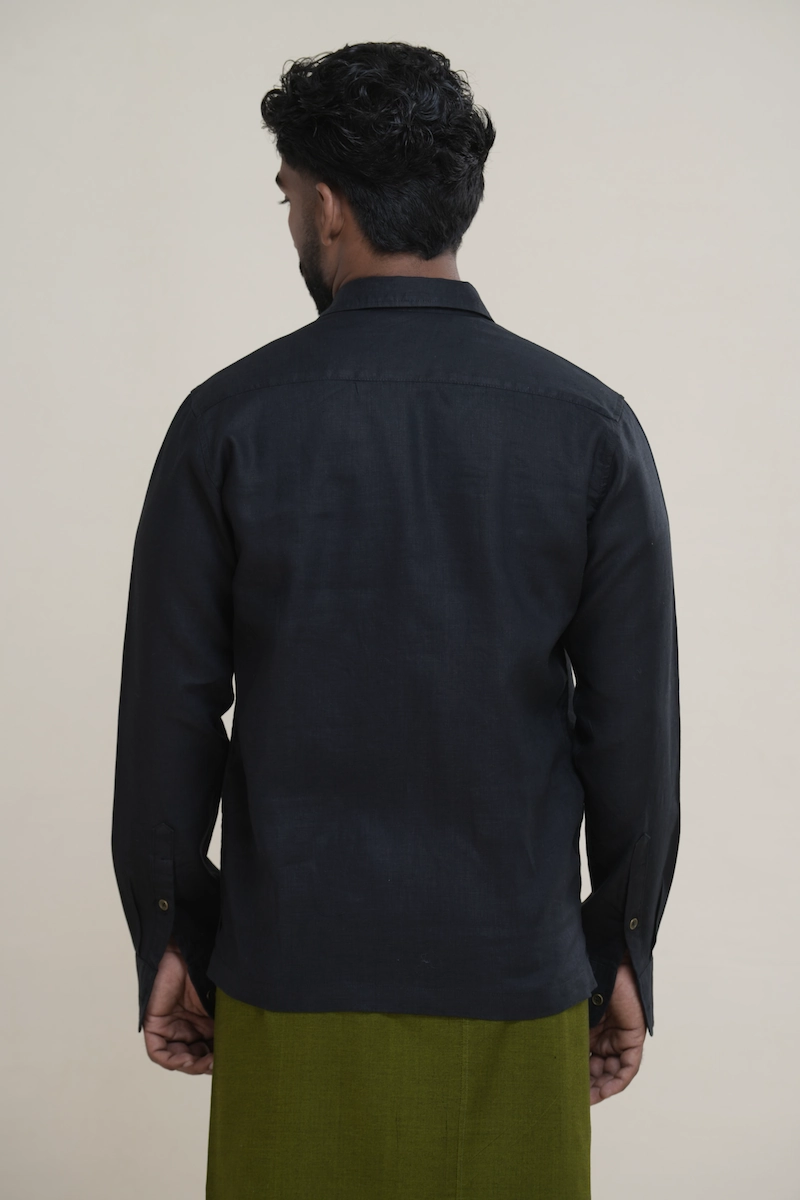 Man wearing a matte black long sleeve utility shirt with four front flap pockets, paired with a patterned sarong