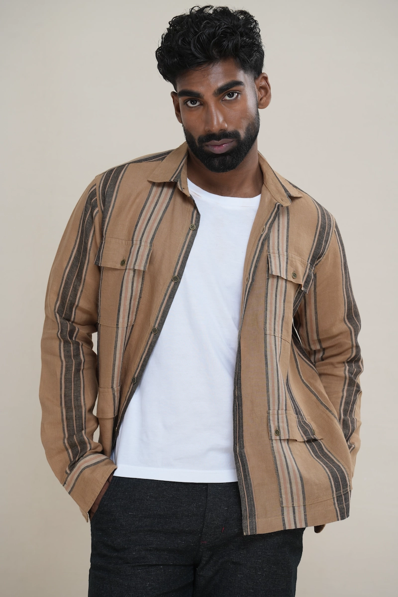Man wearing a tan brown multi-stripe long sleeve utility shirt with four front flap pockets.