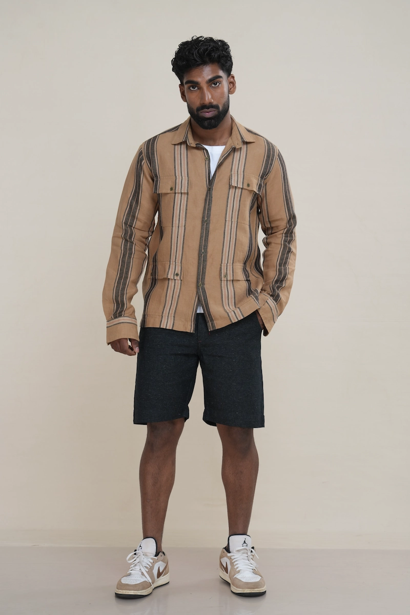 Man wearing a tan brown multi-stripe long sleeve utility shirt with four front flap pockets.