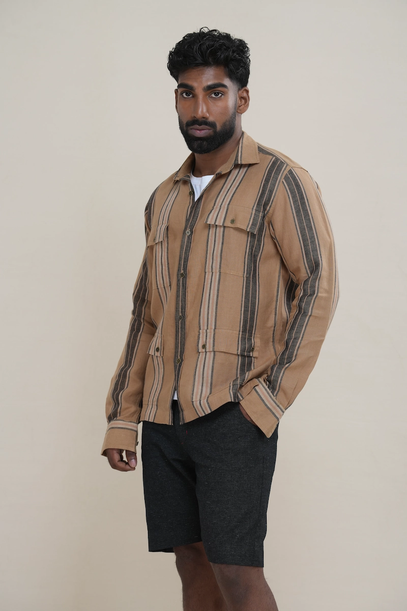 Man wearing a tan brown multi-stripe long sleeve utility shirt with four front flap pockets.