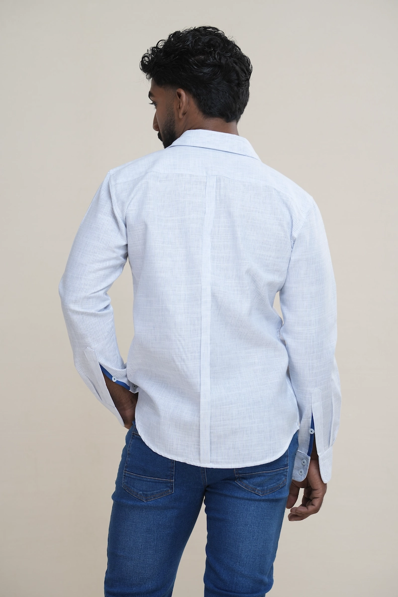 Man wearing a white and light blue pinstripe linen shirt featuring a solid navy contrast collar and white buttons.