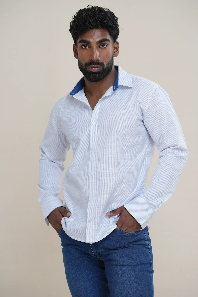 Man wearing a white and light blue pinstripe linen shirt featuring a solid navy contrast collar and white buttons.