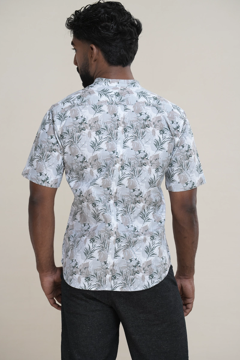 Close-up of a men's cotton Mandarin collar short sleeve shirt with a light grey base and green botanical print, featuring coconut buttons.