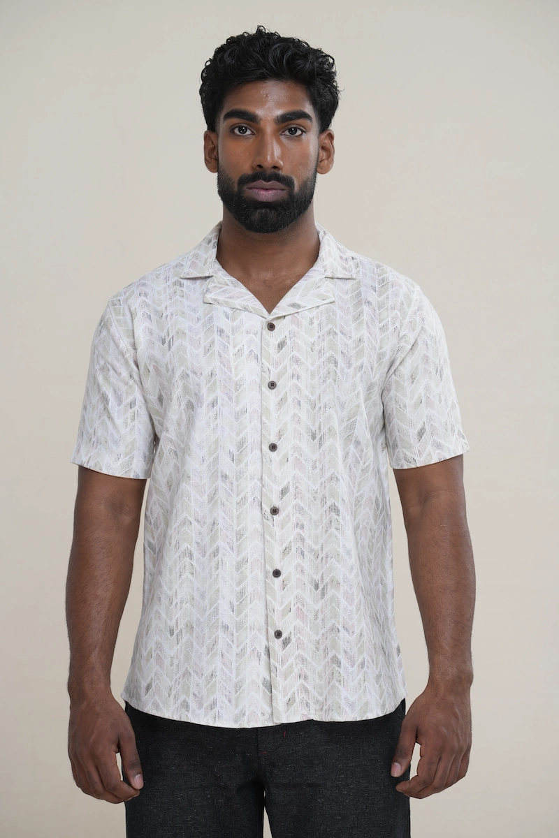 Man wearing a light multi-color chevron print Cuban collar short sleeve shirt with coconut buttons.