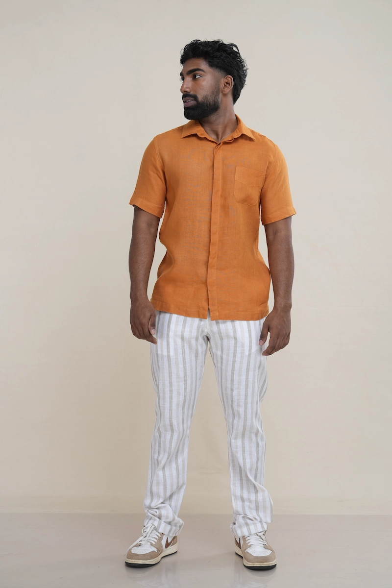 Man wearing a rust brown linen short sleeve shirt with a double placket and chest pocket.