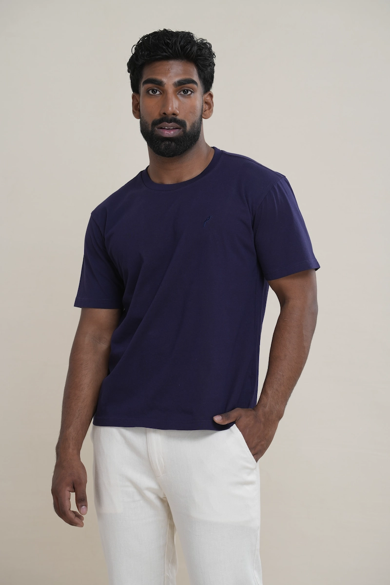 Man wearing a navy blue classic crew neck t-shirt with embroidered parrot logo.