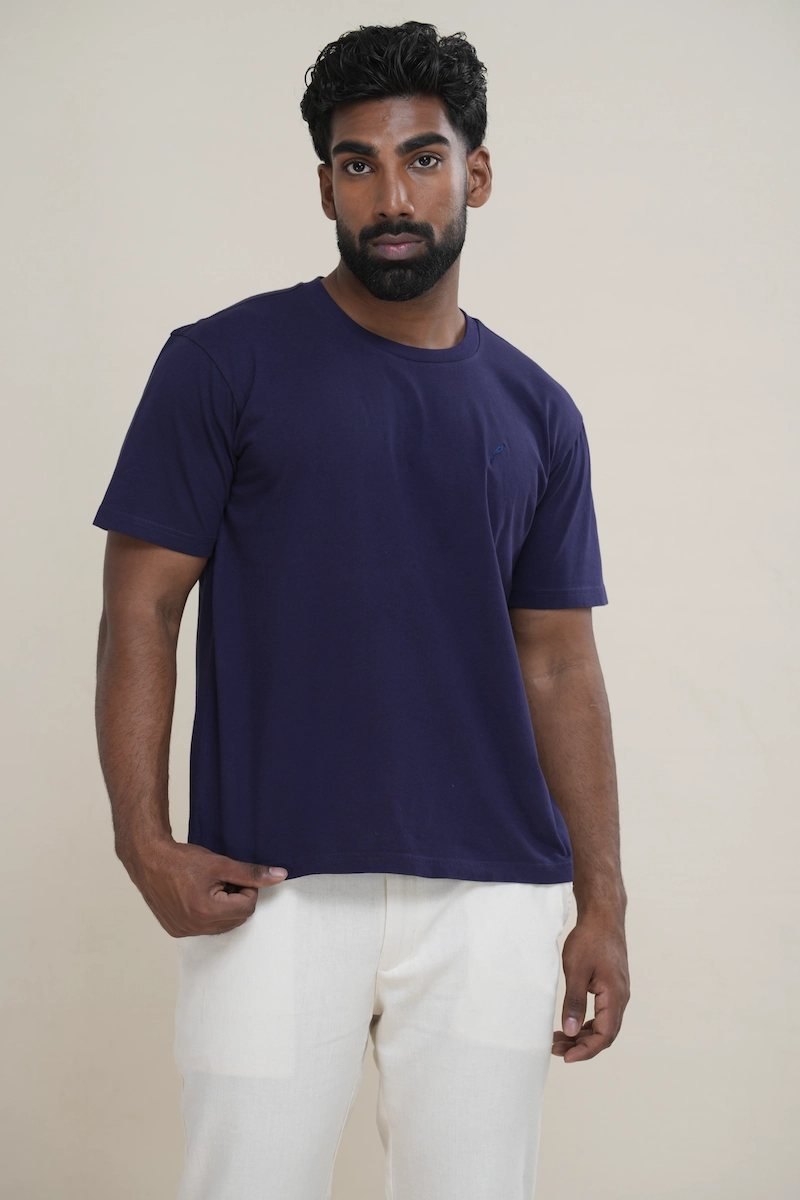 Man wearing a navy blue classic crew neck t-shirt with embroidered parrot logo.