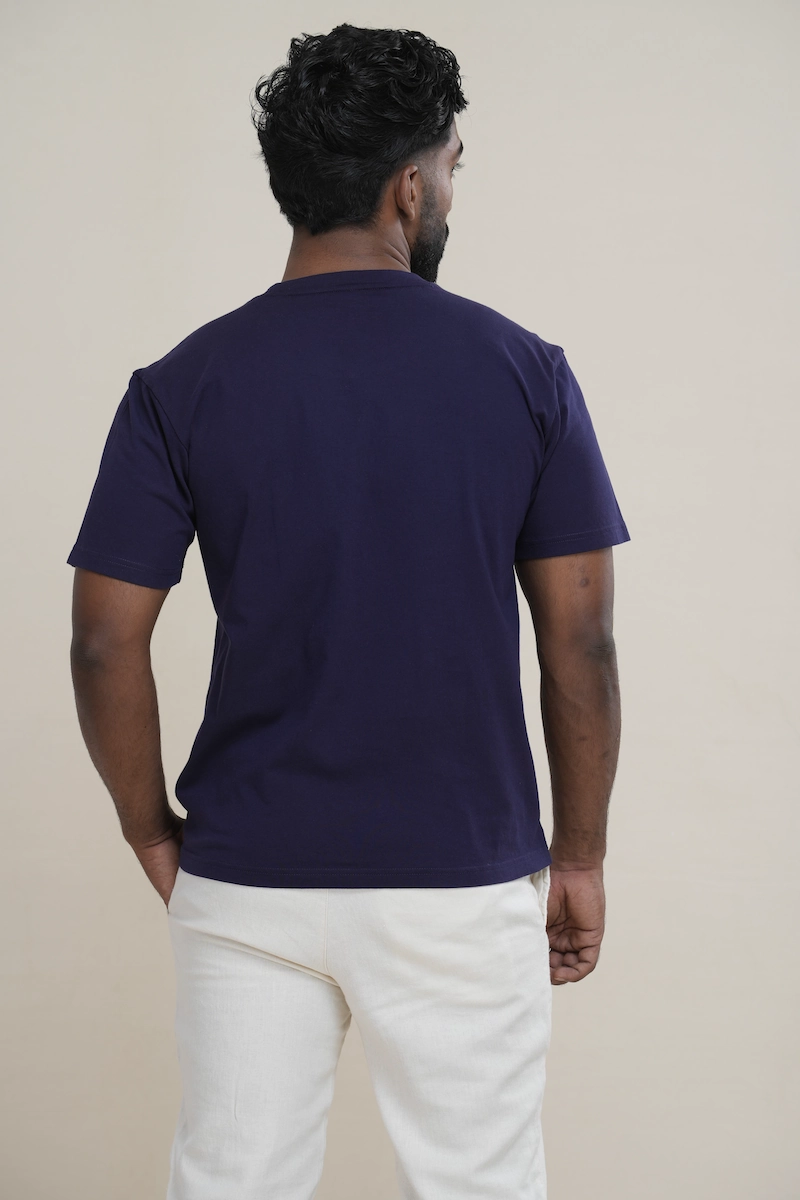 Man wearing a navy blue classic crew neck t-shirt with embroidered parrot logo.