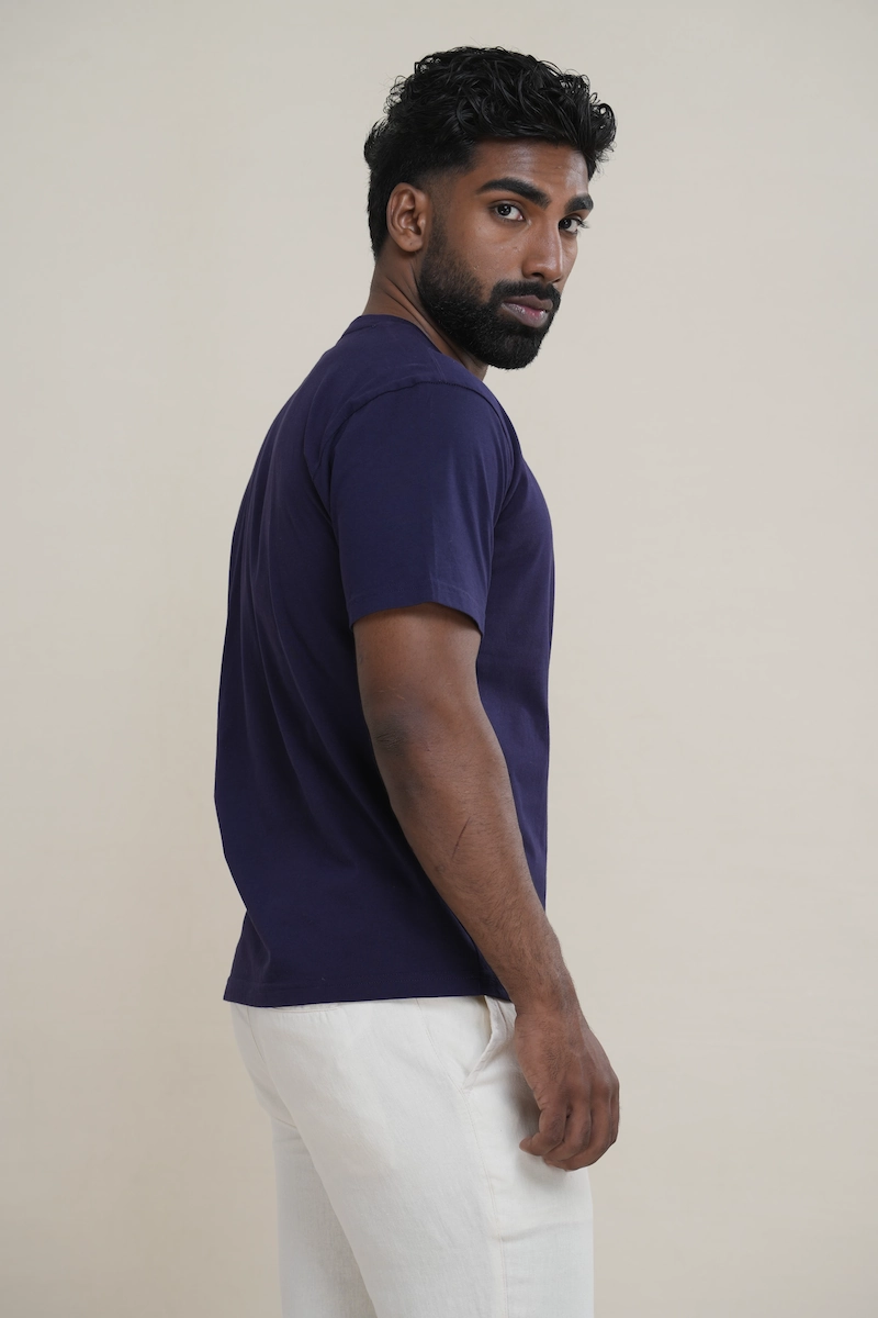 Man wearing a navy blue classic crew neck t-shirt with embroidered parrot logo.
