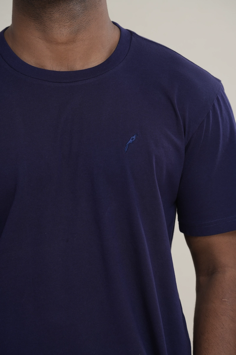 Man wearing a navy blue classic crew neck t-shirt with embroidered parrot logo.