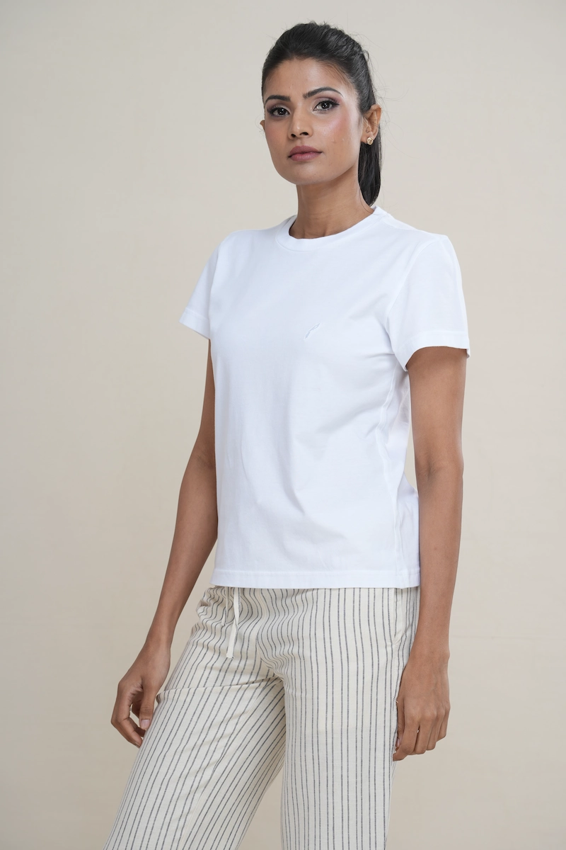 Woman wearing a classic white cotton crew neck t-shirt with a tonal white embroidered logo on the chest.
