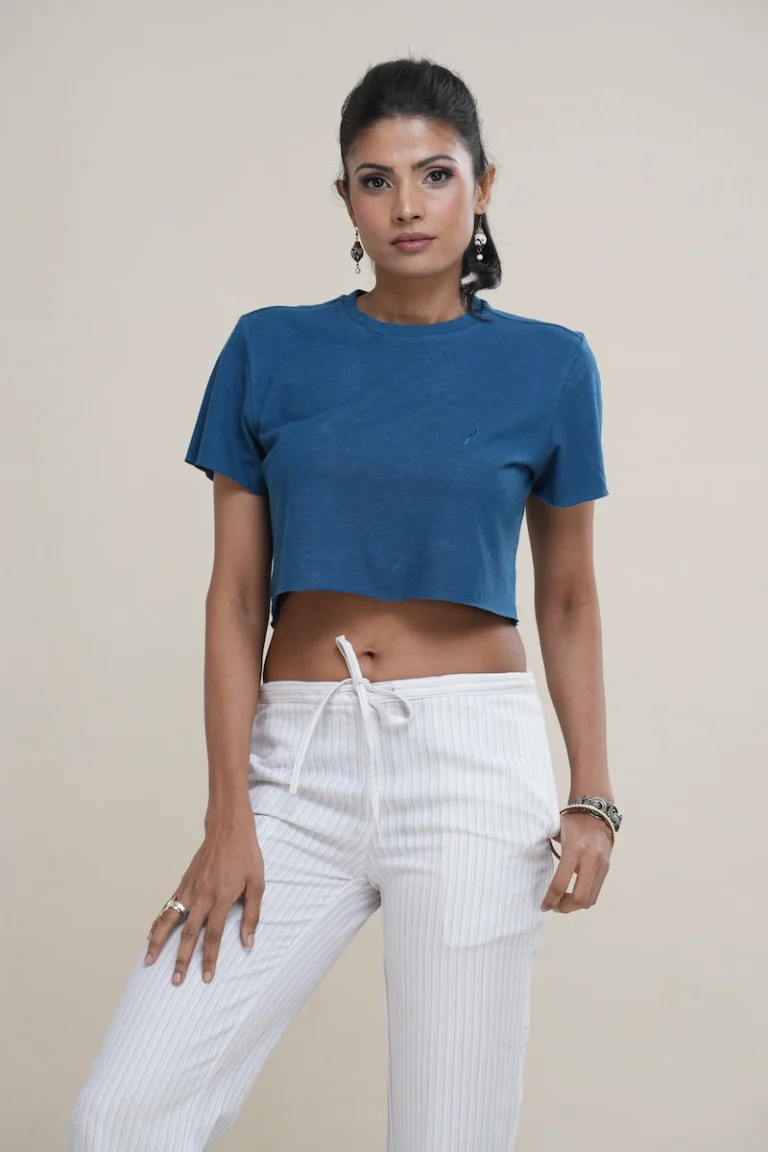 Woman wearing a heathered deep turquoise cotton jersey raw edge cropped t-shirt with a tonal embroidered logo.