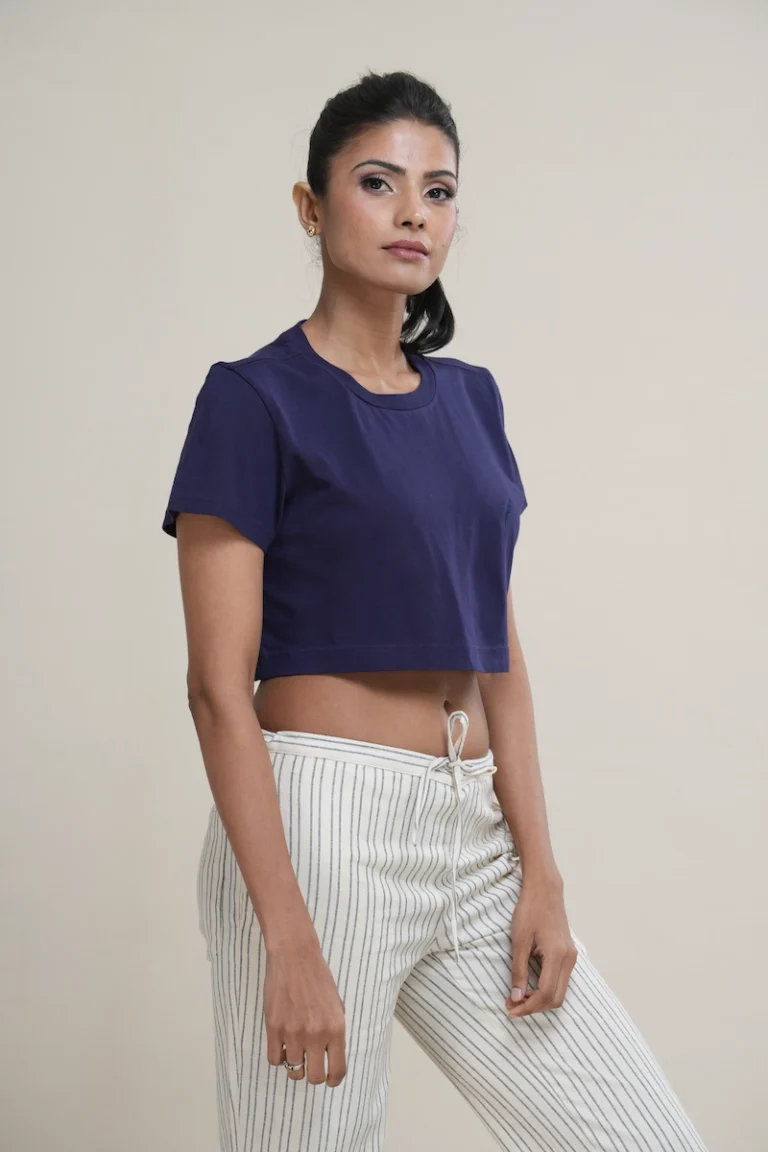 Woman wearing a navy blue cotton cropped t-shirt with a tonal navy embroidered logo on the chest.