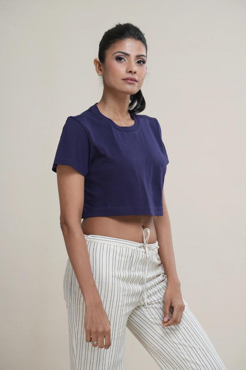 Woman wearing a navy blue cotton cropped t-shirt with a tonal navy embroidered logo on the chest.