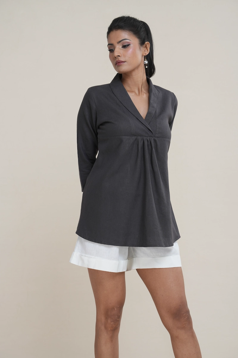 Woman wearing a charcoal brown linen-cotton blend shawl collar tunic with an empire waist and three-quarter sleeves.