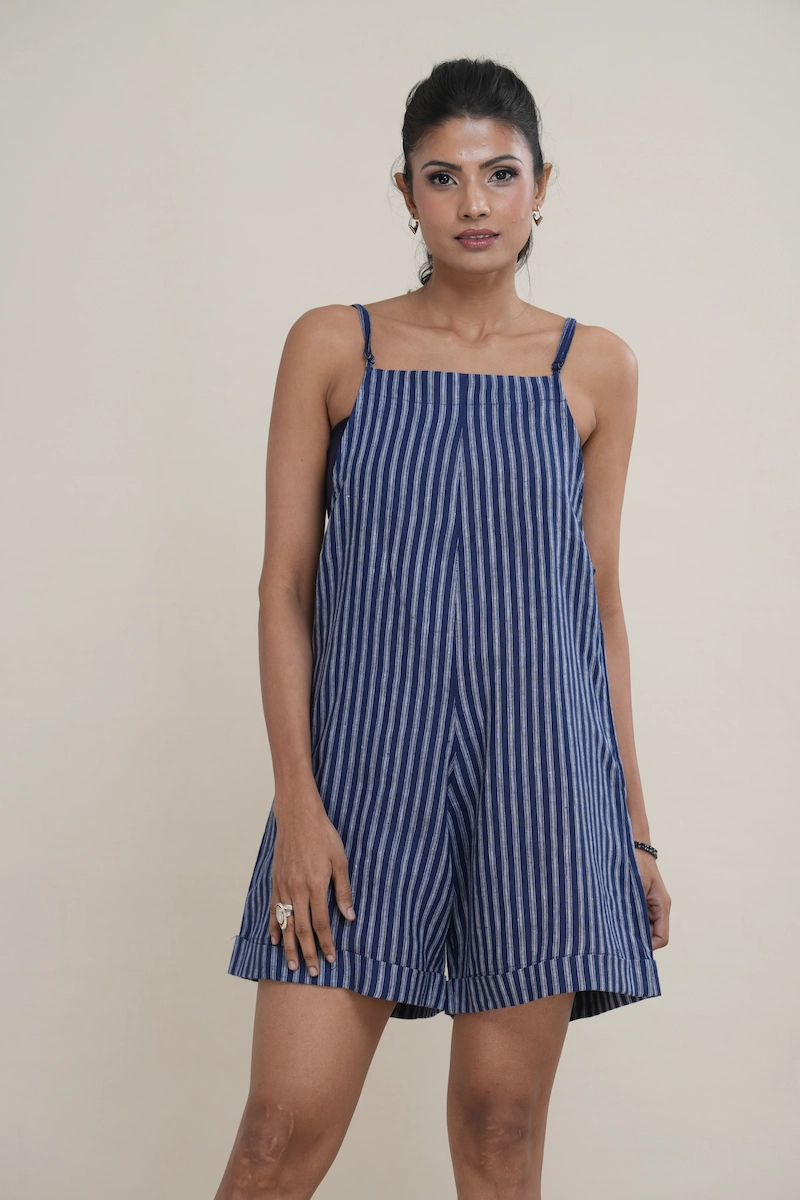 Woman wearing an indigo blue and white striped linen-cotton blend cami romper with side pockets.