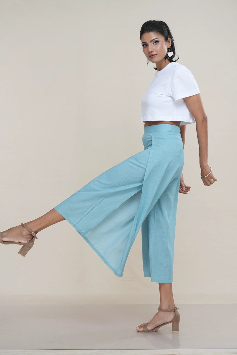 Woman wearing light turquoise linen-cotton blend wide-leg culottes with a high side slit, showcasing movement, the elegant high side slit detail on light turquoise wide-leg cropped pants.