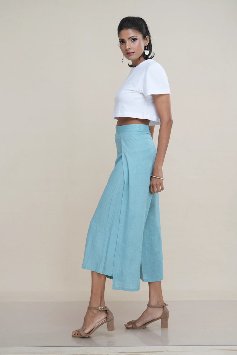 Woman wearing light turquoise linen-cotton blend wide-leg culottes with a high side slit, showcasing movement, the elegant high side slit detail on light turquoise wide-leg cropped pants.