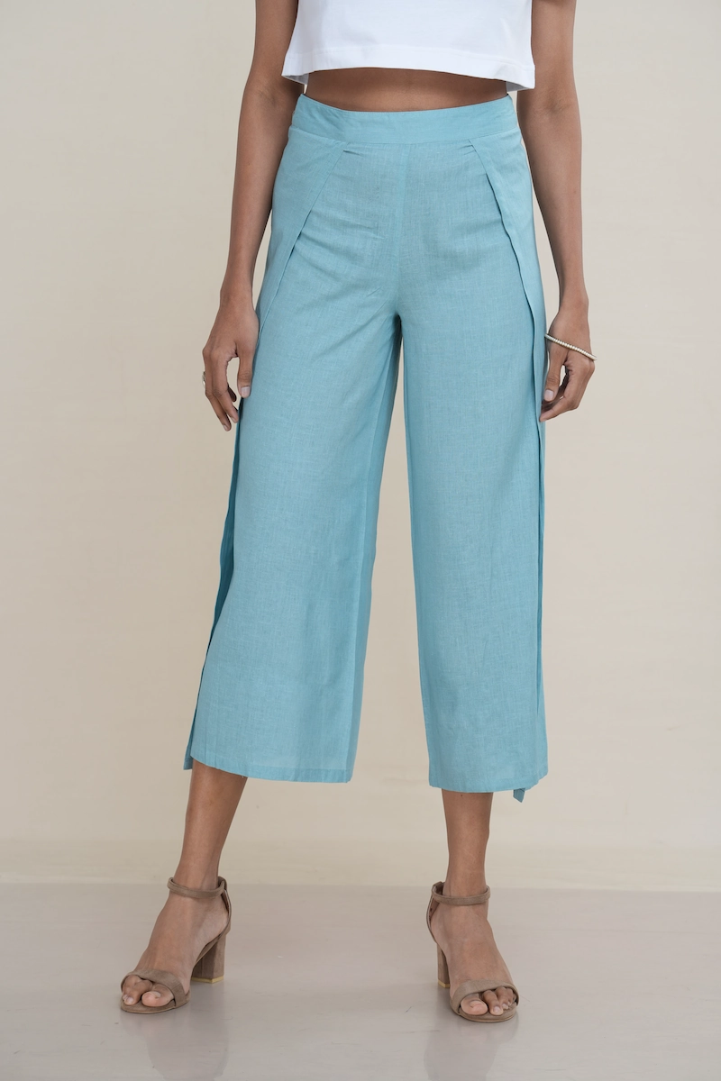 Woman wearing light turquoise linen-cotton blend wide-leg culottes with a high side slit, showcasing movement, the elegant high side slit detail on light turquoise wide-leg cropped pants.