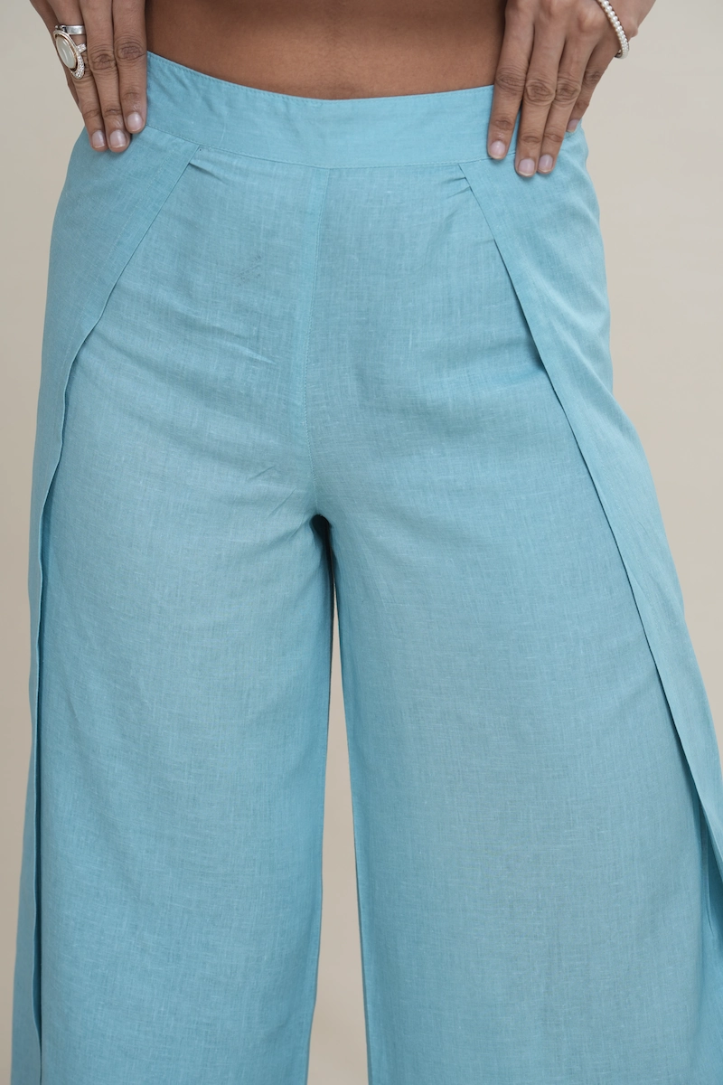 Woman wearing light turquoise linen-cotton blend wide-leg culottes with a high side slit, showcasing movement, the elegant high side slit detail on light turquoise wide-leg cropped pants.