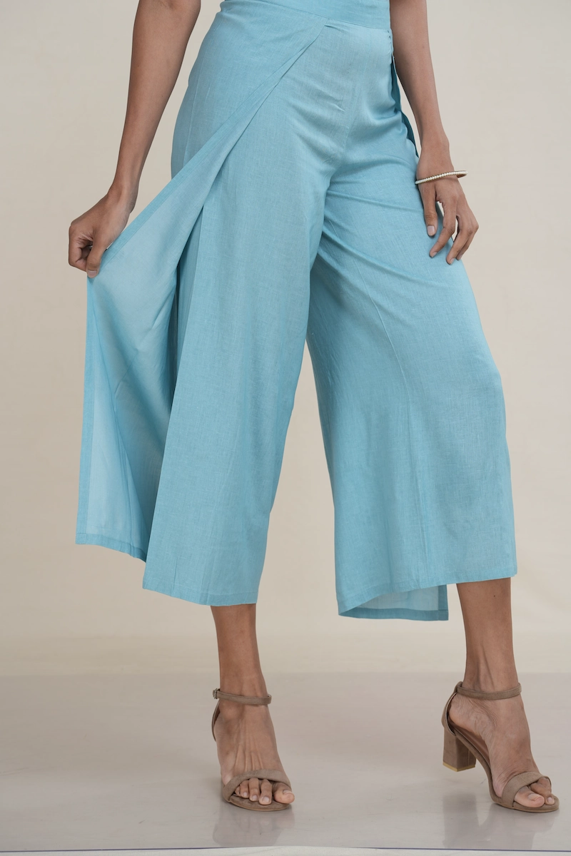 Woman wearing light turquoise linen-cotton blend wide-leg culottes with a high side slit, showcasing movement, the elegant high side slit detail on light turquoise wide-leg cropped pants.