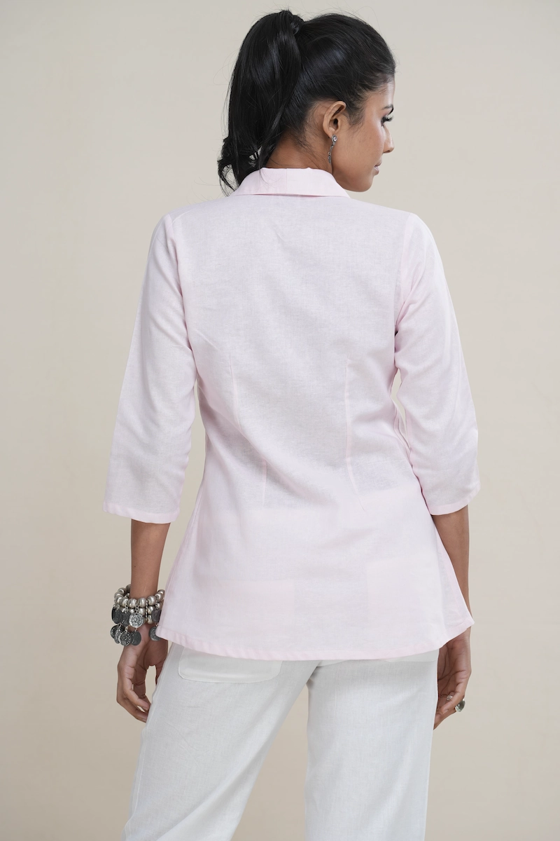 Woman wearing a pastel pink linen-Cotton blend shawl collar tunic top with an empire waist and three-quarter sleeves, the elegant shawl collar and empire waist detail on a pastel pink linen tunic top.