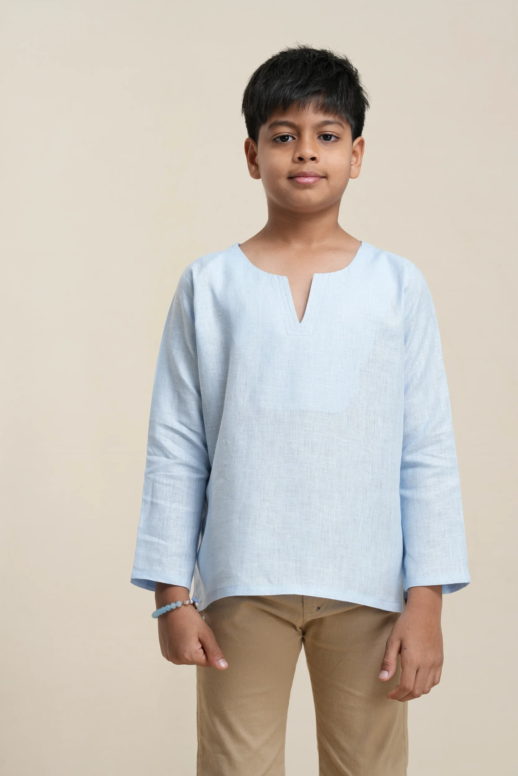 Boys' long sleeve kurta in sky blue linen with notch neckline, relaxed fit, paired with beige trousers on model