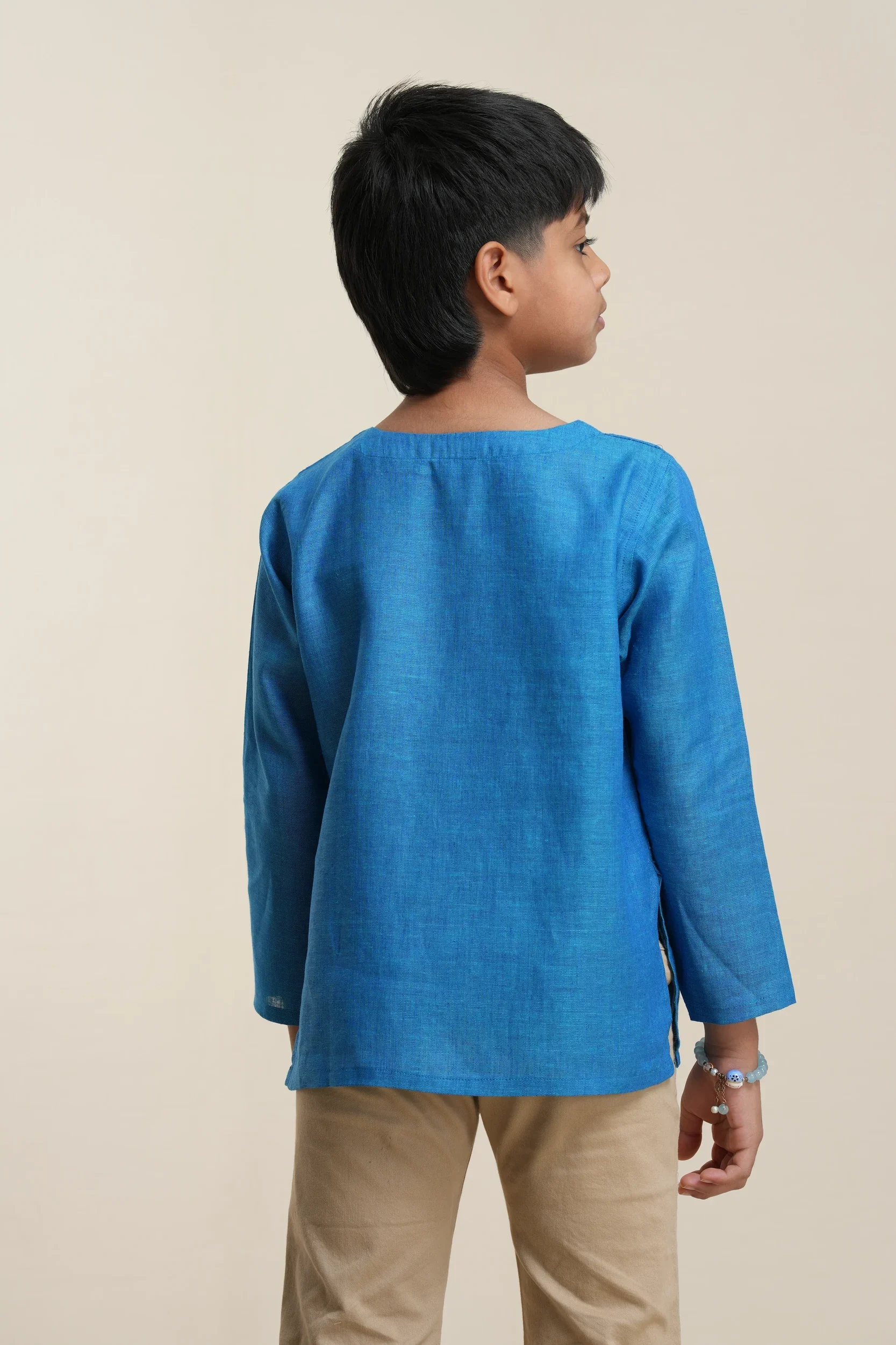 Back view of boys' long sleeve kurta in cerulean blue linen fabric, showing relaxed fit and natural drape