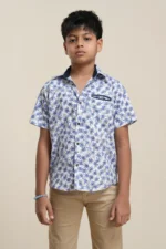 Boys' white linen short sleeve shirt with blue palm tree print, navy collar detail, front button closure, model wearing