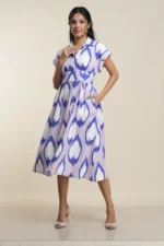 Woman wearing blue ikat leaf print collared midi dress in cotton blend, front view full length on beige background