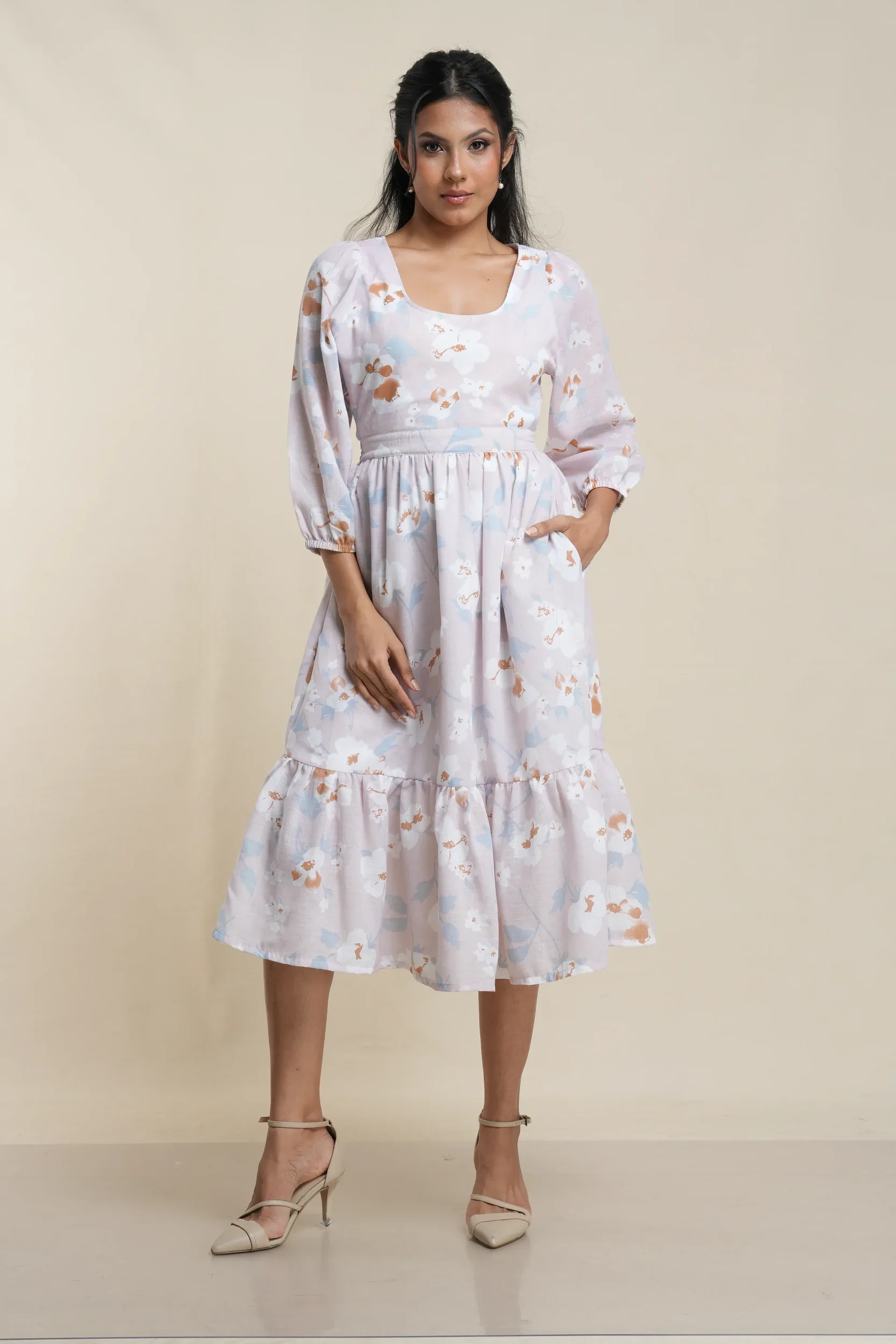 Front view of women's tiered midi dress in white and lilac floral print cotton blend with puff sleeves and ruffle hem