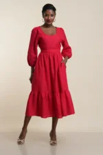 Women's tiered midi dress in scarlet red linen with puff sleeves, gathered waist, ruffle hem, and side pockets worn by model