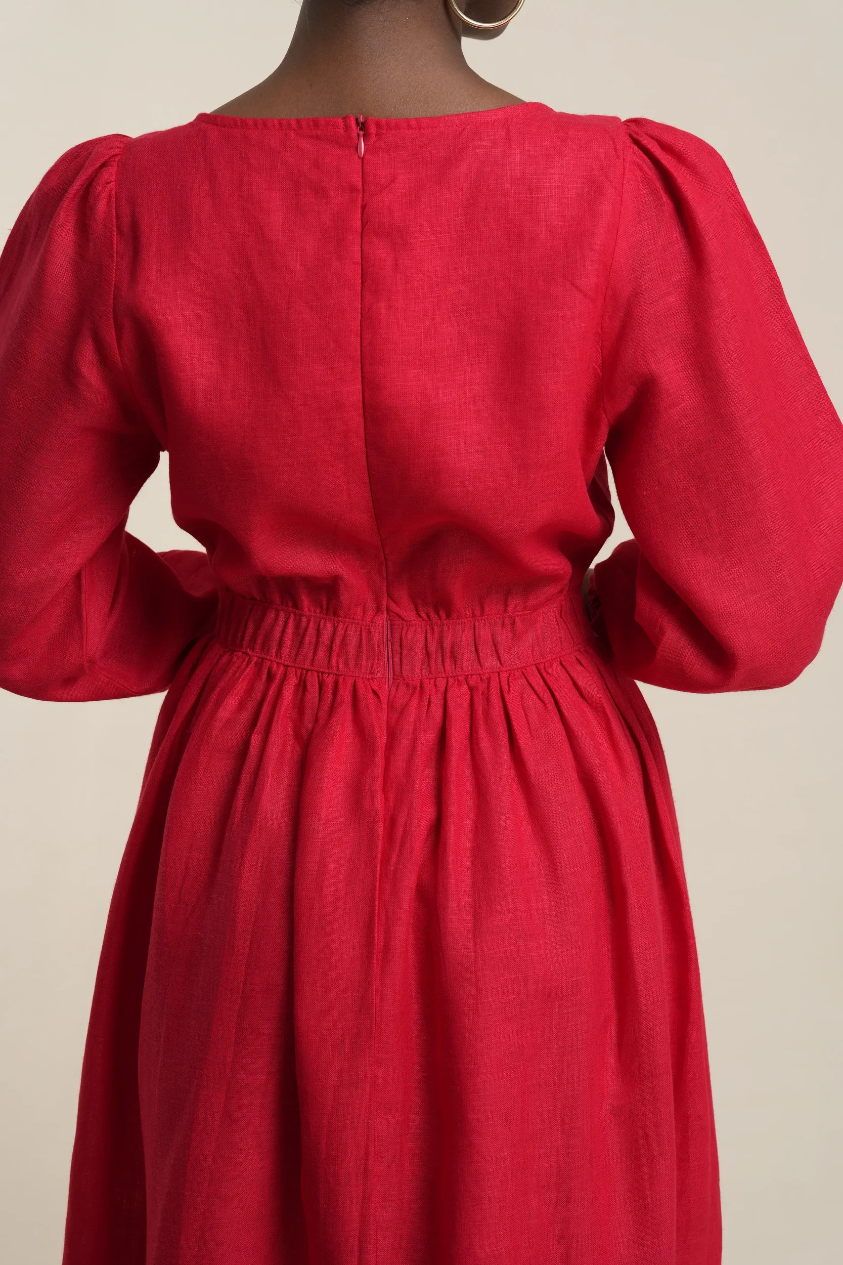 Back view of women's tiered midi dress in scarlet red linen with puff sleeves, gathered waist, and center back zipper