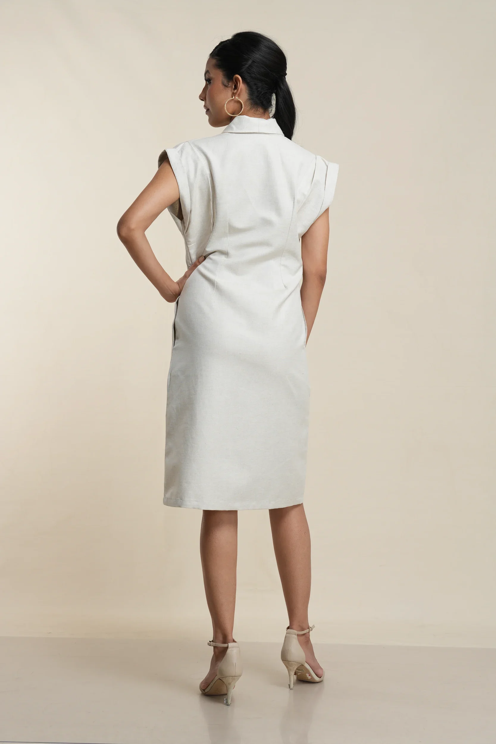 Back view of ecru linen cotton blend button-front shirt dress showing clean tailoring, cap sleeves, and knee length hem