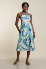 Front view of women's halter neck midi dress in blue and green leaf print on linen blend fabric with pleated texture