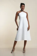 White linen blend halter neck midi dress with twisted neckline detail, A-line silhouette, modeled against neutral background