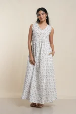 Model wearing white sleeveless maxi dress with delicate botanical print pattern, cotton blend fabric, V-neck design